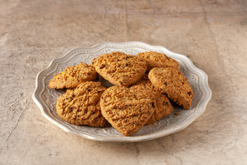 oatmeal cookies in the shape of hearts on a round ceramic plate, on the table, selective focus