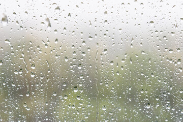 weather background - rain drops and trickles of rain closeup on window glass in heavy rain