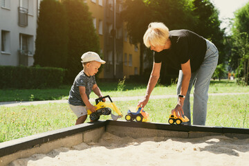 Grandmother and child having fun together, playing in sandbox. Generation and childhood concept. Happy family symbol