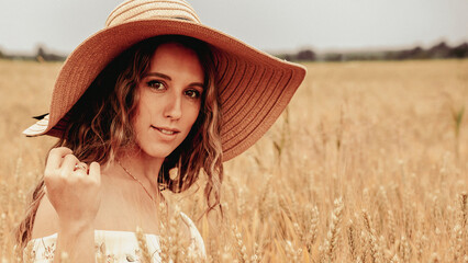 Girl wheat field summer. Happy young woman in sun hat in summer wheat field at sunset. Nature, summer holidays, vacation and people concept.