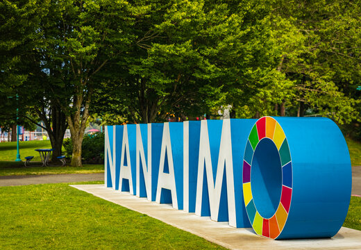 The name of the city of Nanaimo in large 3D letters sitting on the ground in a park in summer day