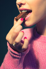 Beautiful young woman eating chocolate cookies	
