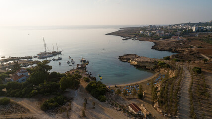 Aerial bird's eye view of Green bay Protaras, Paralimni, Famagusta, Cyprus. Famous tourist attraction diving location rock beach with boats, sea restaurant, water sports on summer holidays, from above