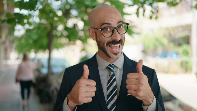 Young hispanic man executive smiling confident doing ok sign with thumbs up at street