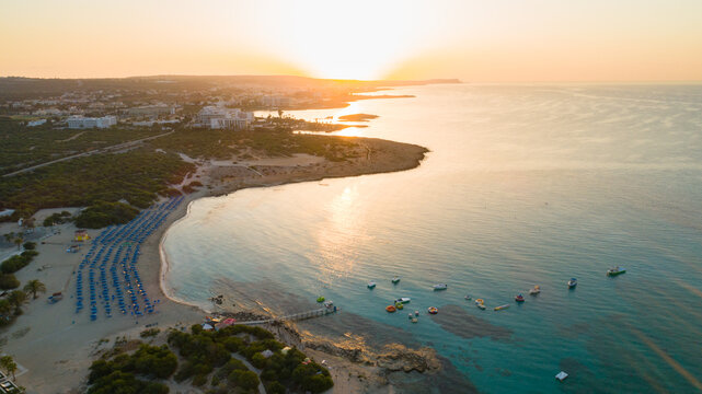 Aerial bird's eye view of Landa beach, Ayia Napa, Famagusta, Cyprus. Landmark tourist attraction golden sand bay at sunrise with boats anchored between Makronissos and nissi in Agia Napa, from above.	