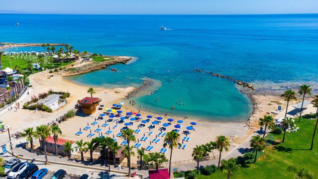 Aerial bird's eye view Pernera beach Protaras, Paralimni, Famagusta, Cyprus. The tourist attraction golden sand bay with sunbeds, water sports, hotels, restaurants, people swimming in sea from above. © f8grapher