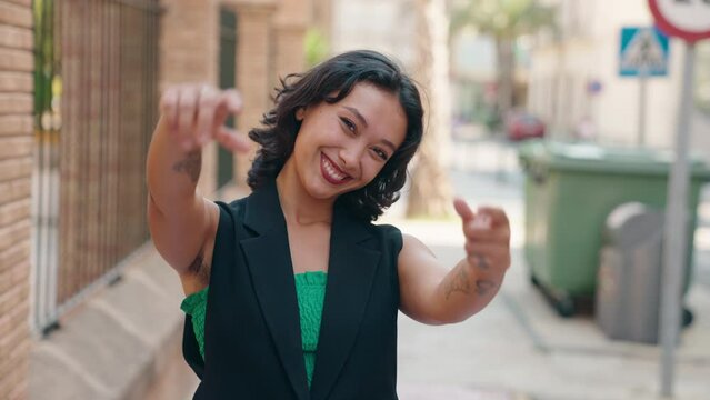 Young beautiful hispanic woman smiling confident doing photo gesture with hands at street