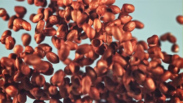 A pile of peanuts rises up and falls. On a blue background. Filmed is slow motion 1000 fps.