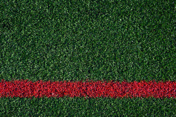 Closeup of artificial grass turf on a recreational sports field, with a red stripe, as a graphic...