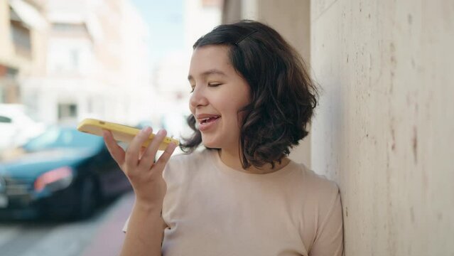 Young woman smiling confident talking on the smartphone at street
