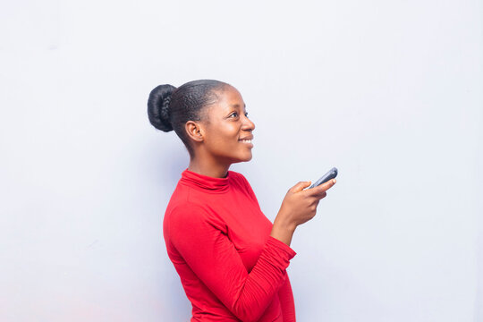Beautiful black African girl isolated over white background holding cellphone and standing side ways