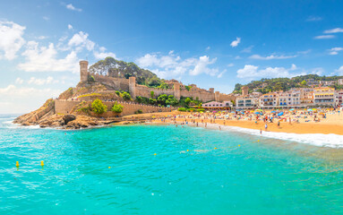 Fototapeta na wymiar Panoramic view of the 12th century castle, the sandy beach, whitewashed town and turquoise waters of the Costa Brava coast along the Mediterranean Sea, at Tossa de Mar, Spain.