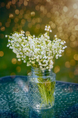 Bouquet of spring flower lilies of the valley on a natural green background of the garden.
