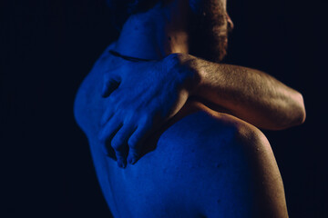 man rubbing his back, muscle pain, blue light