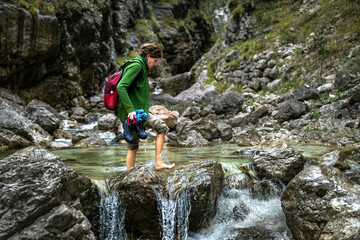 Walking Barefoot Over An Alpine River for a Backpack Adventurous Woman