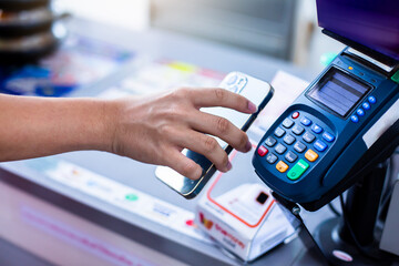 Selective focus to customer's hand is using mobile phone to scan to pay for service at counter service in supermarket.