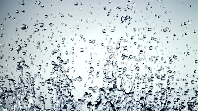 Splashes of water soar up and fall. On a blue background. Filmed is slow motion 1000 fps.