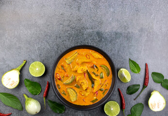 Red curry with chicken, thai eggplant, lime leaves, chili pepper, lime on a gray background, top view, copy space. Thai food top view.