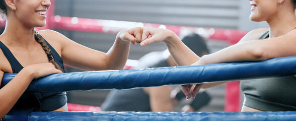 Closeup of happy women showing support, motivation and unity with fist bump at the gym or fitness...