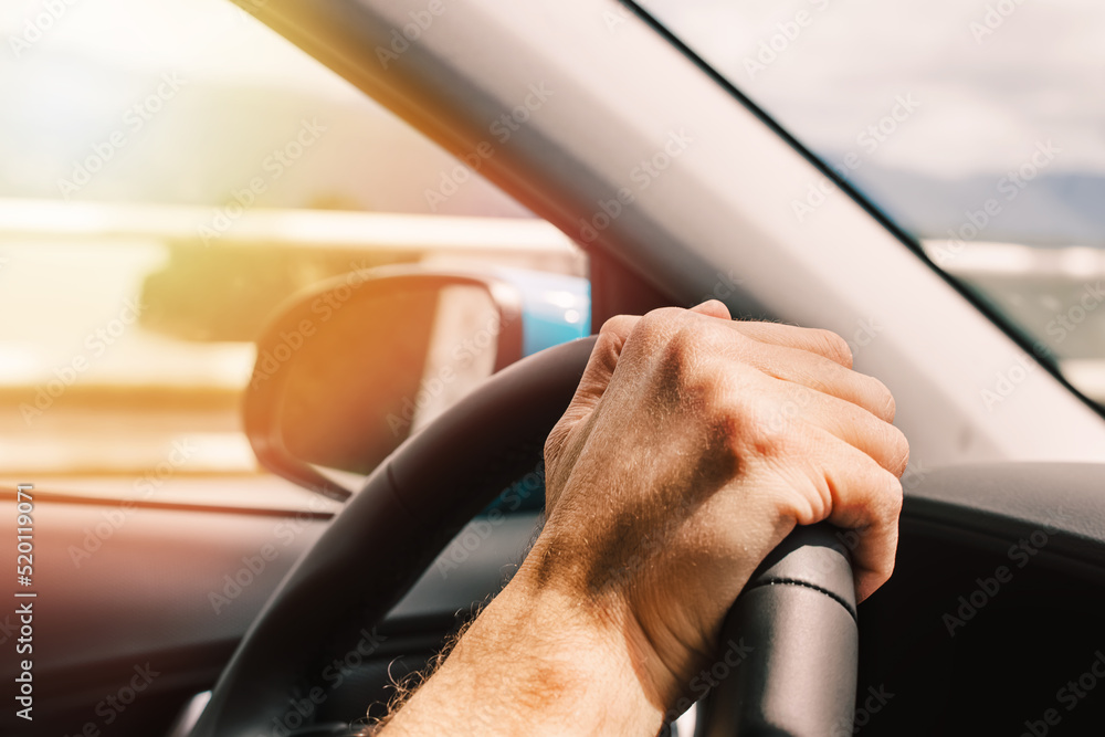 Wall mural man's hand on the steering wheel close-up