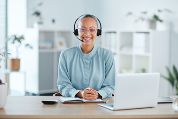 Happy and confident call center agent sitting in front of a laptop while wearing a headset in an office. Portrait of a cheerful saleswoman using web chat to assist customer sales and service support