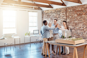 Team of happy architect engineers celebrating together with a high five after completing a small...