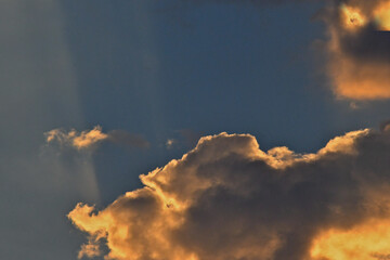 Faint sun rays over small backlit cumulus clouds 