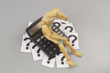 Financial problems and find solution concept. Wooden figurine  on calculator with question marks on...