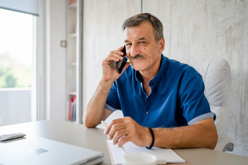 one man senior entrepreneur active caucasian male making a phone call talking while sitting at the...