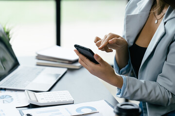 Asian businesswoman in formal suit in office happy and cheerful during using smartphone and working.