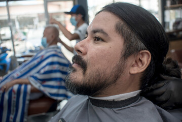A bearded man in his late 30s and of mixed raced at the barbershop. Getting ready for a haircut or...