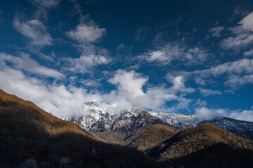 Beautiful scenic view on snow peaks in the distance.Blue sky with clouds above moutains peaks.