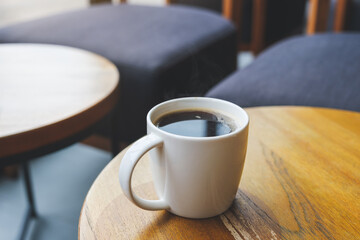 Closeup image of a white cup of hot coffee on wooden table in cafe
