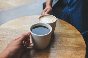 Closeup image of a couple people clinking coffee cups together in cafe