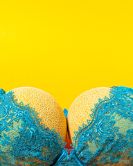 Funny, big organic juicy melons in the sexy green bra with yellow background. Visual concept  idea.