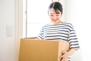 段ボールを運ぶ女性（通販・宅配便）
