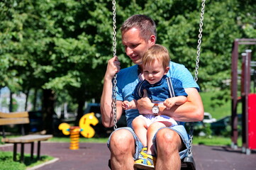 Father swinging with his little boy on playground