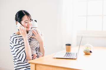 赤ちゃんの世話をしながら電話する女性
