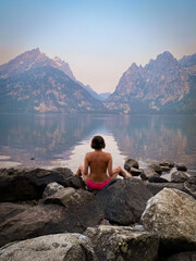 a naked woman sitting on a rock in the lake