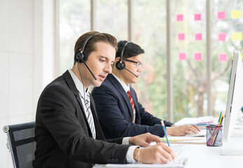 Group of customer service call center with headset and writing note to seek advice problems for customer. Group of technical support operator customer service in the office