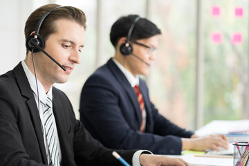 Group of customer service call center with headset and writing note to seek advice problems for customer. Group of technical support operator customer service in the office