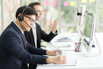 Group of customer service call center with headset and writing note to seek advice problems for...
