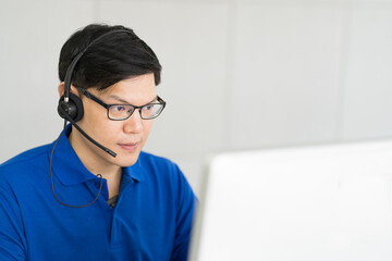 Asian male with headset working at call center department. Man technical support operator with team...