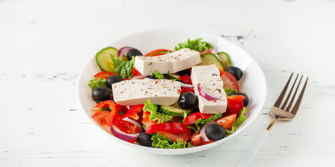 Greek salad of fresh cucumber, tomato, sweet pepper, lettuce, red onion, feta cheese and olives with olive oil. Healthy food