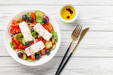 Greek salad of fresh cucumber, tomato, sweet pepper, lettuce, red onion, feta cheese and olives with olive oil. Healthy food. Top view