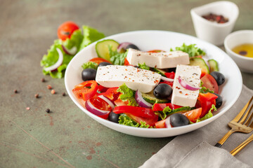 Greek salad of fresh cucumber, tomato, sweet pepper, lettuce, red onion, feta cheese and olives with olive oil. Healthy food