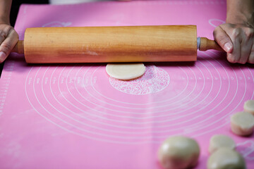 Tread the wooden rolling pin on the dough