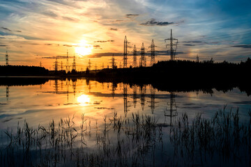 Fototapeta na wymiar Sunset at coast of the lake with electric towers. Nature summer landscape.