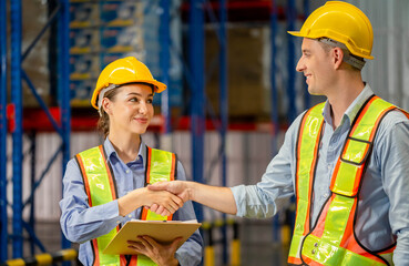 Warehouse worker shaking hands with his colleague at the industrial storage, Worker in uniform...