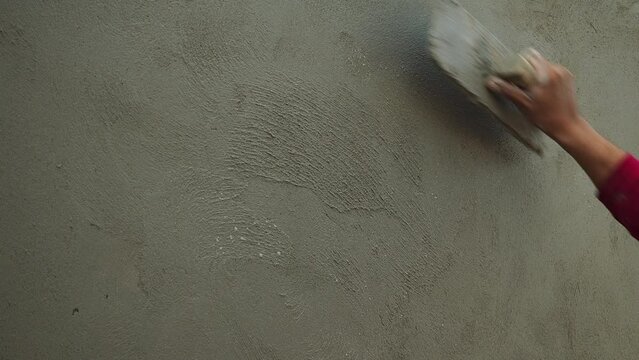 The plasterer applies the plaster to the wall with a spatula.